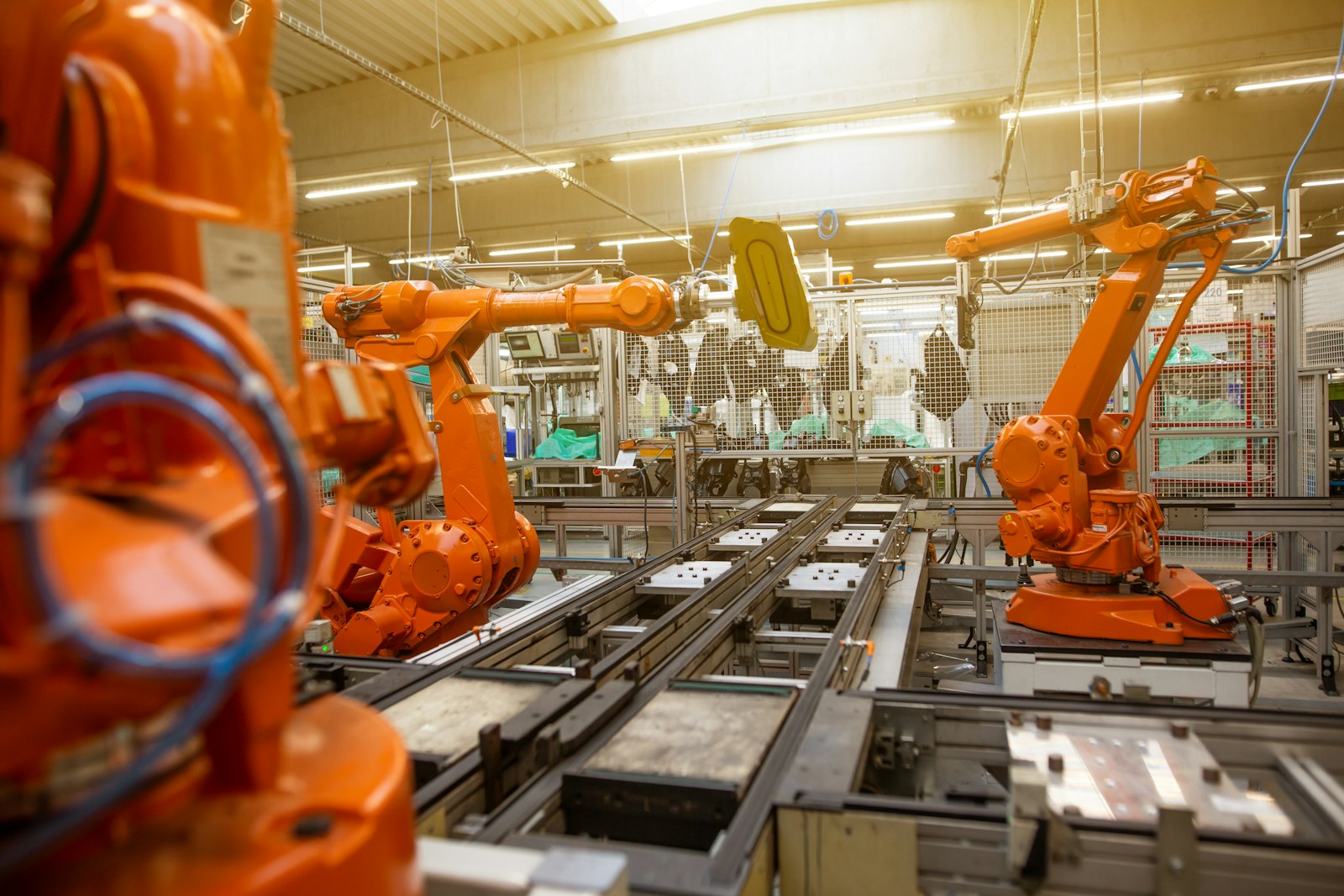 Orange industrial robots on a factory floor